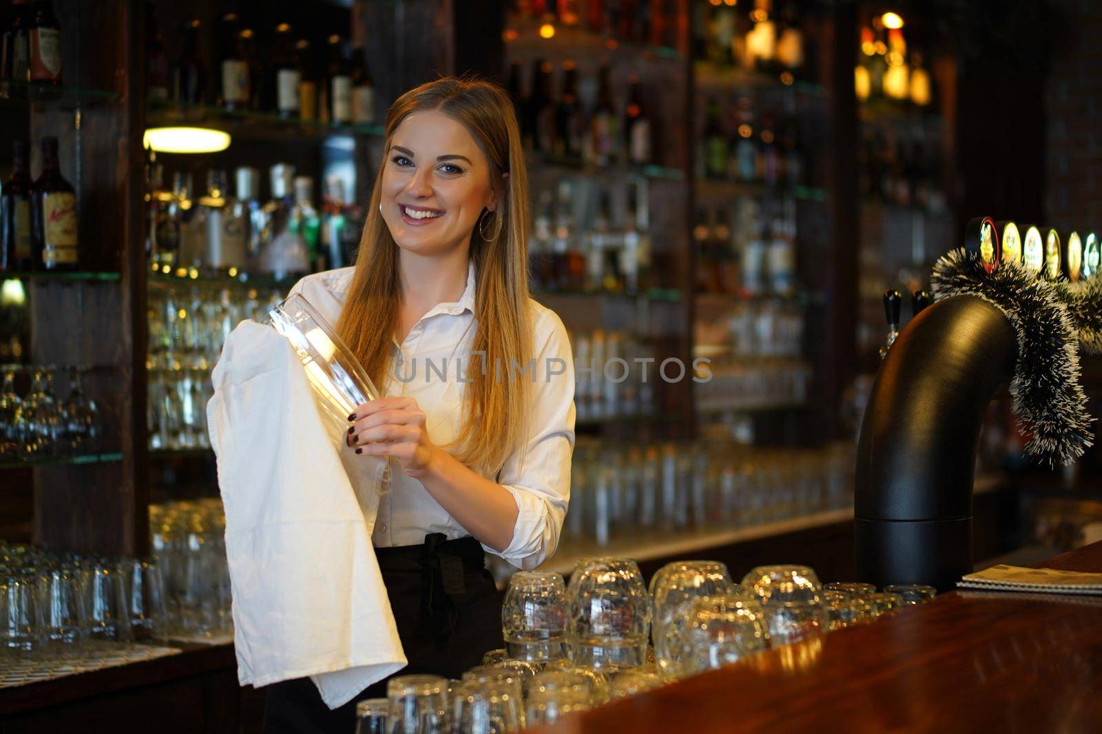 Portrait of happy woman who works as a bartender at bar.