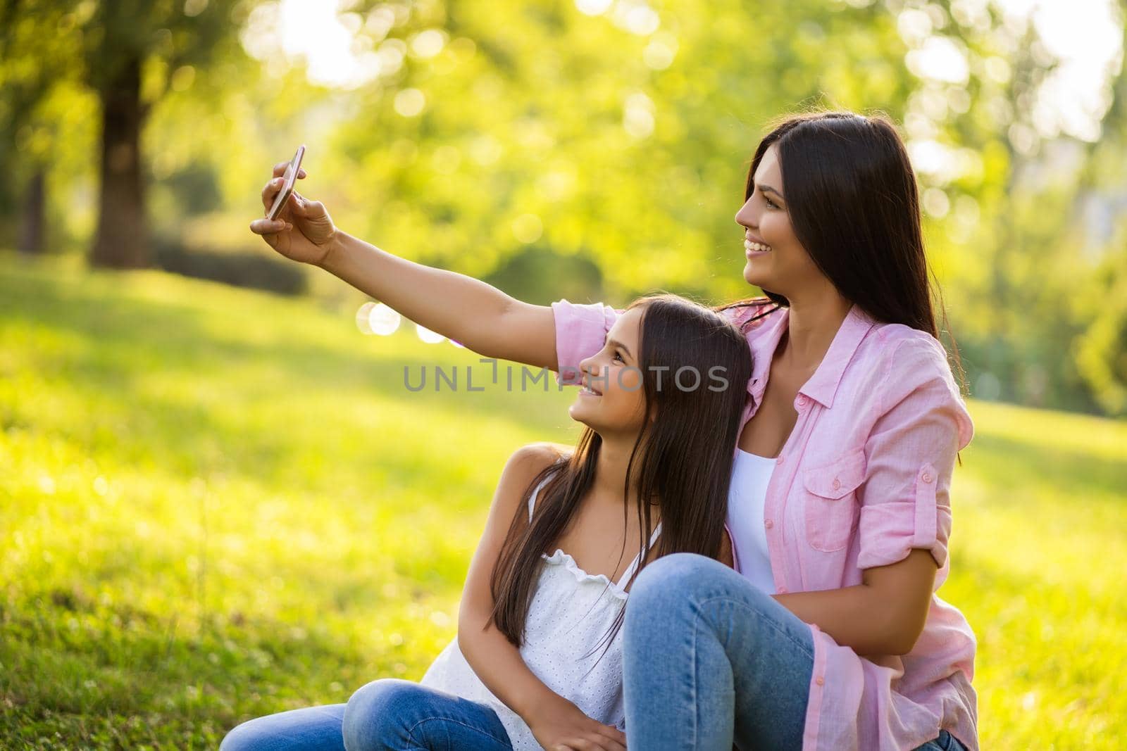 Happy family having nice time in park together. They are taking selfie.