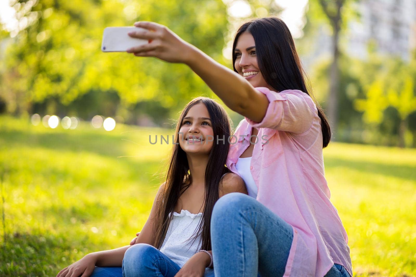 Happy family having nice time in park together. They are taking selfie.