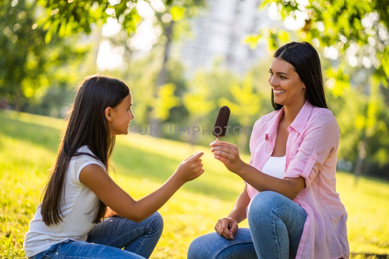 Happy family having nice time in park together. Little girl is eating ice cream.