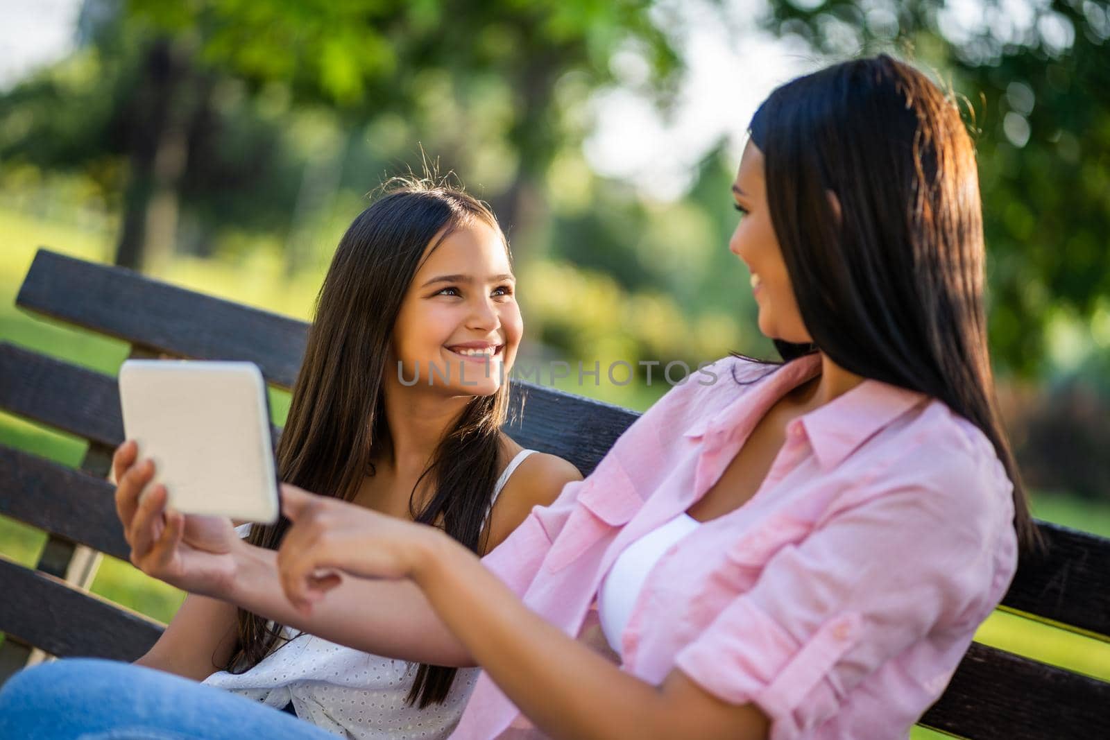 Happy family having nice time in park together. They are using digital tablet.