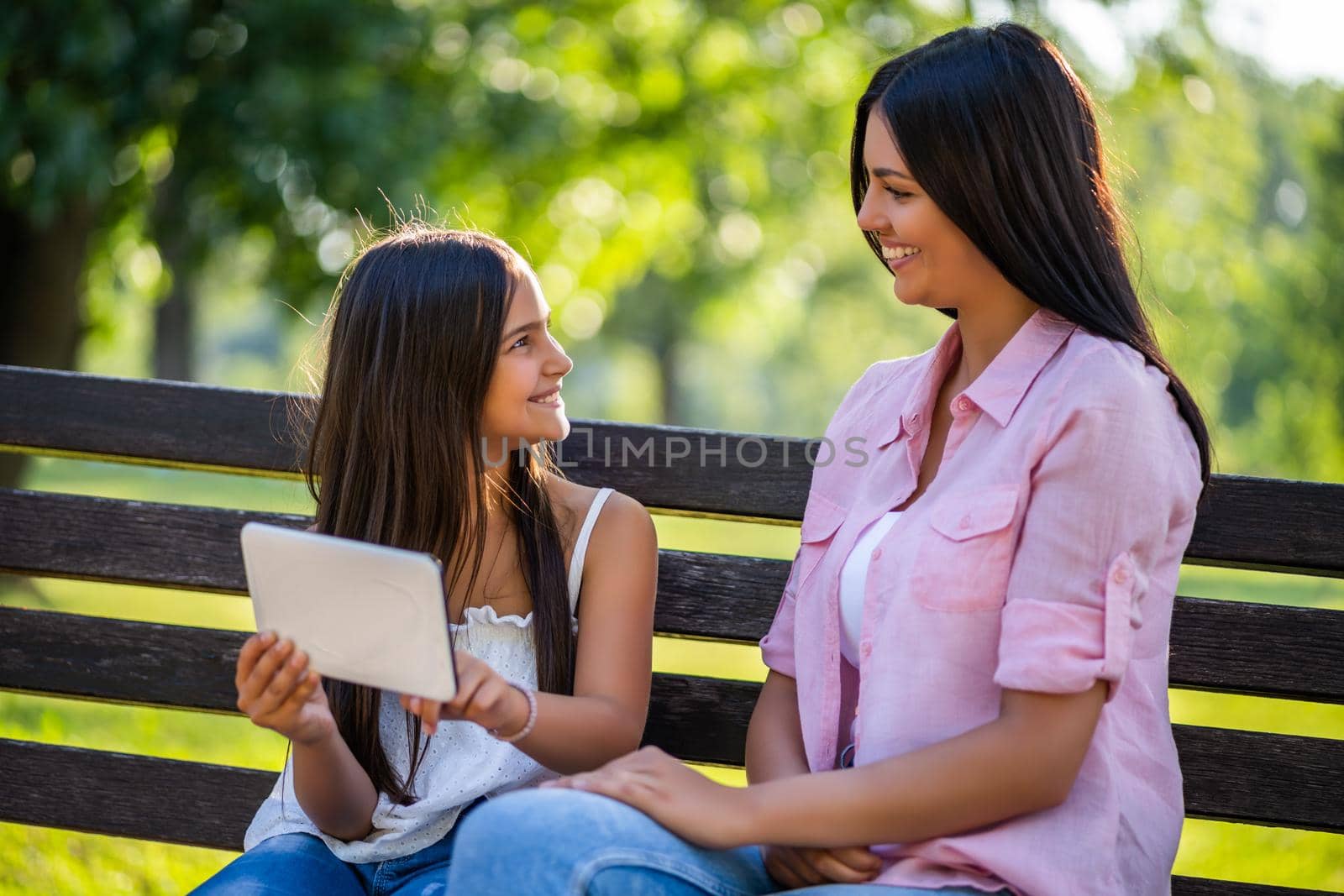 Happy family having nice time in park together. They are using digital tablet.