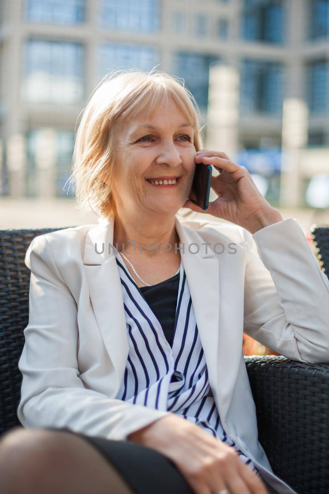 Senior businesswoman is talking on phone in cafe.