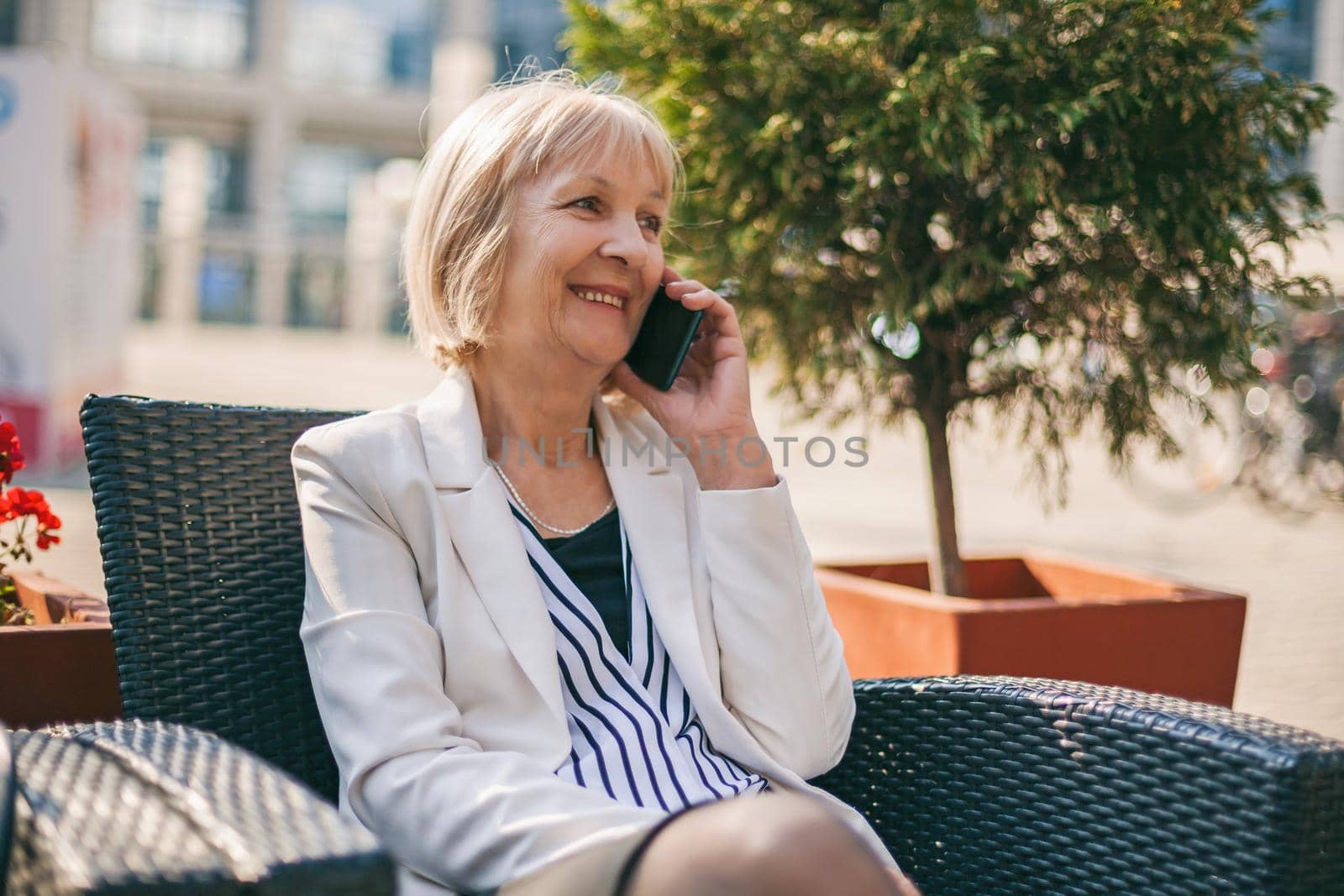 Senior businesswoman is talking on phone in cafe.