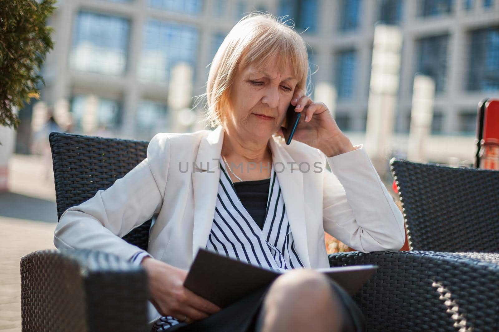 Senior businesswoman is talking on phone in cafe.