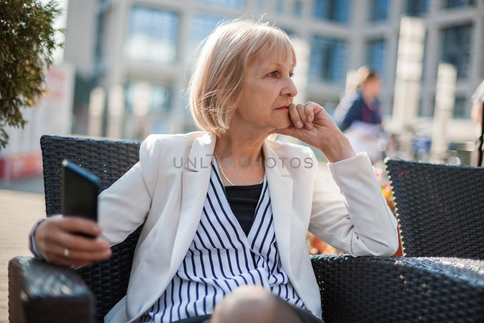 Senior businesswoman is sitting in cafe and searching for job on internet.