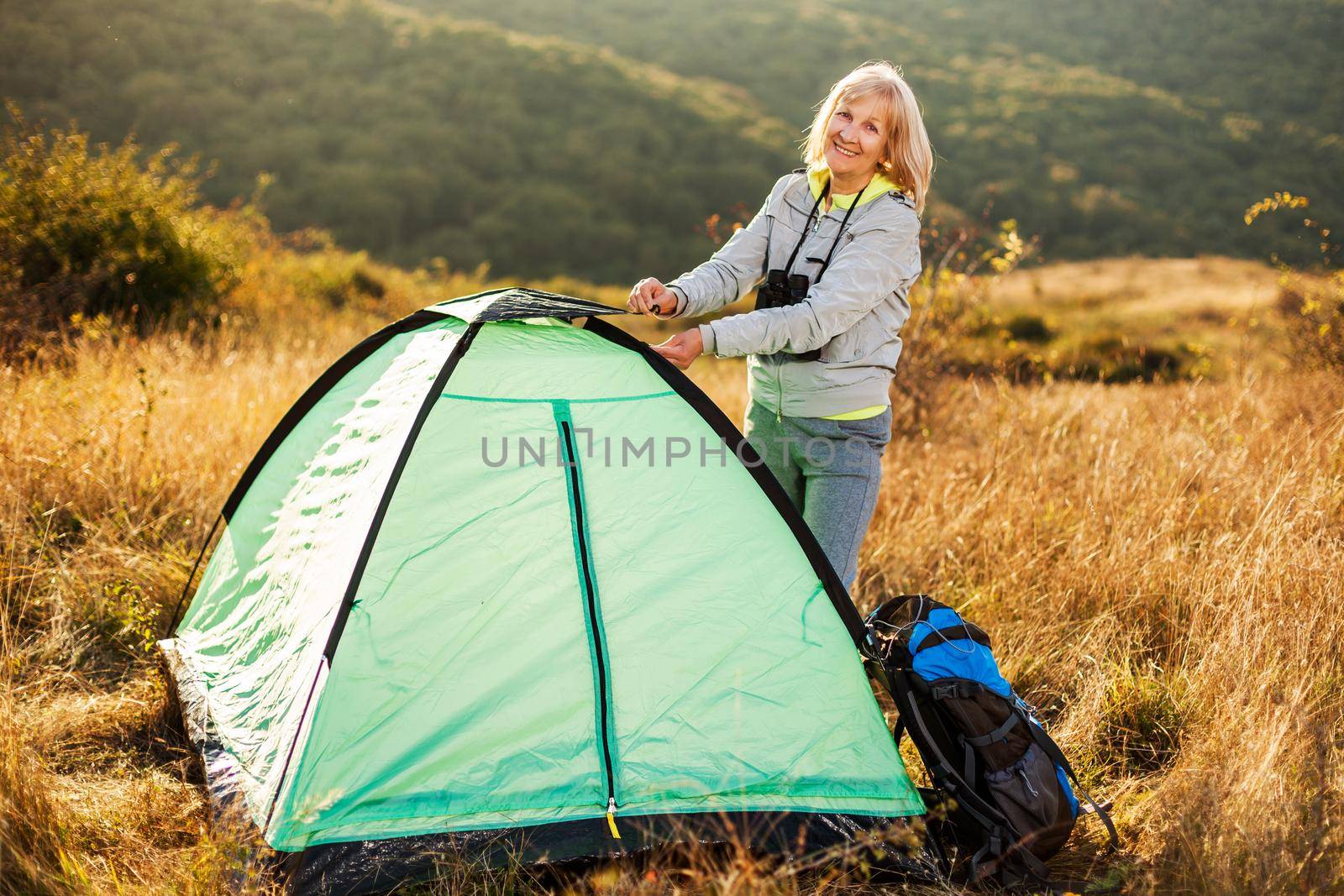 Senior woman is camping in mountain. Active retirement.