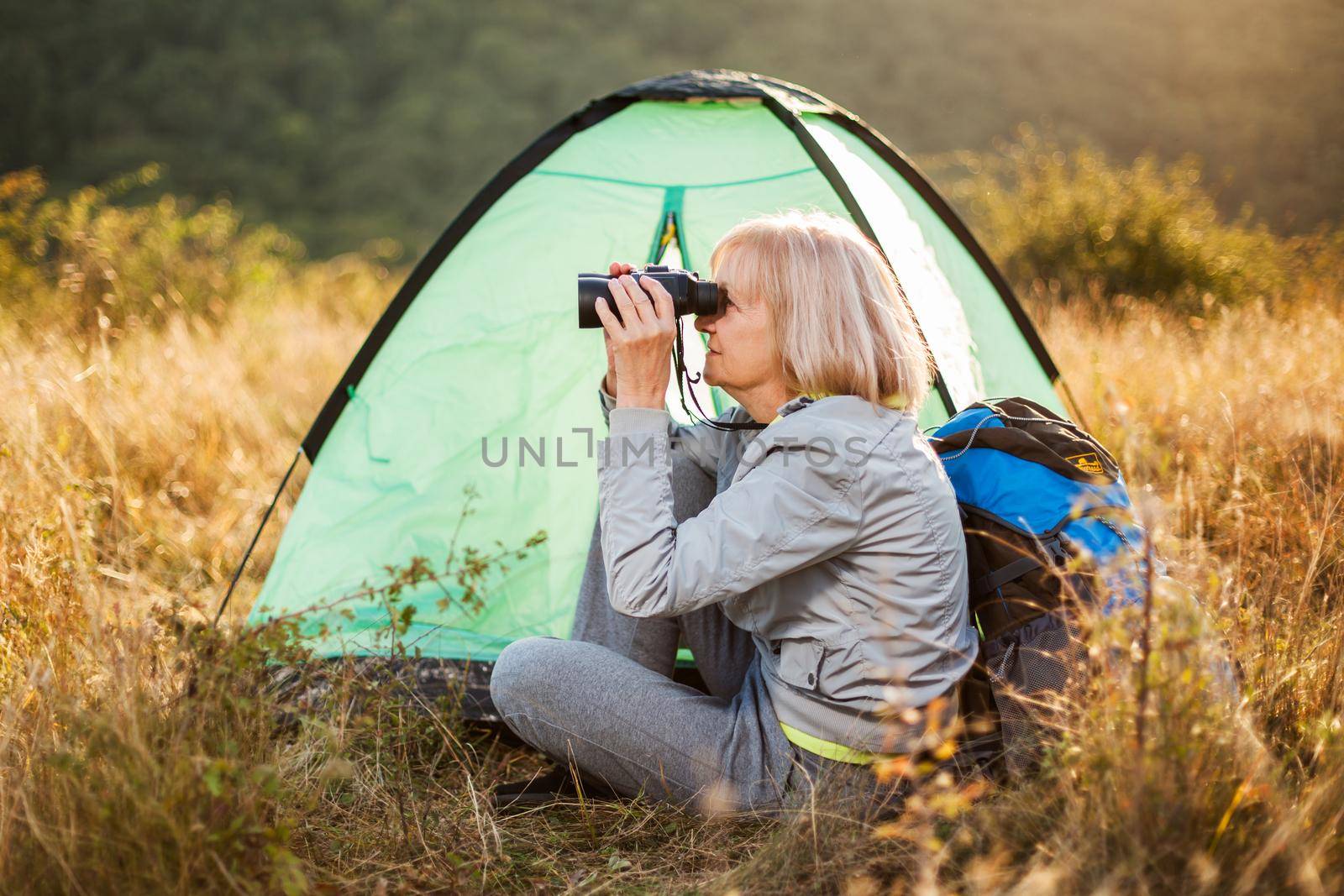 Senior woman is camping in mountain. Active retirement.