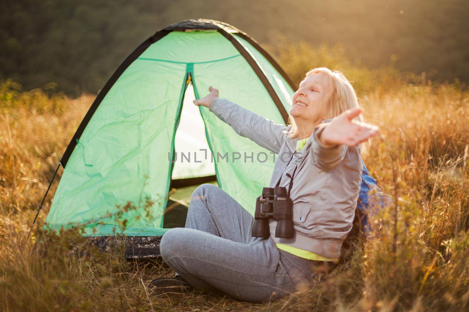 Senior woman is camping in mountain. Active retirement.