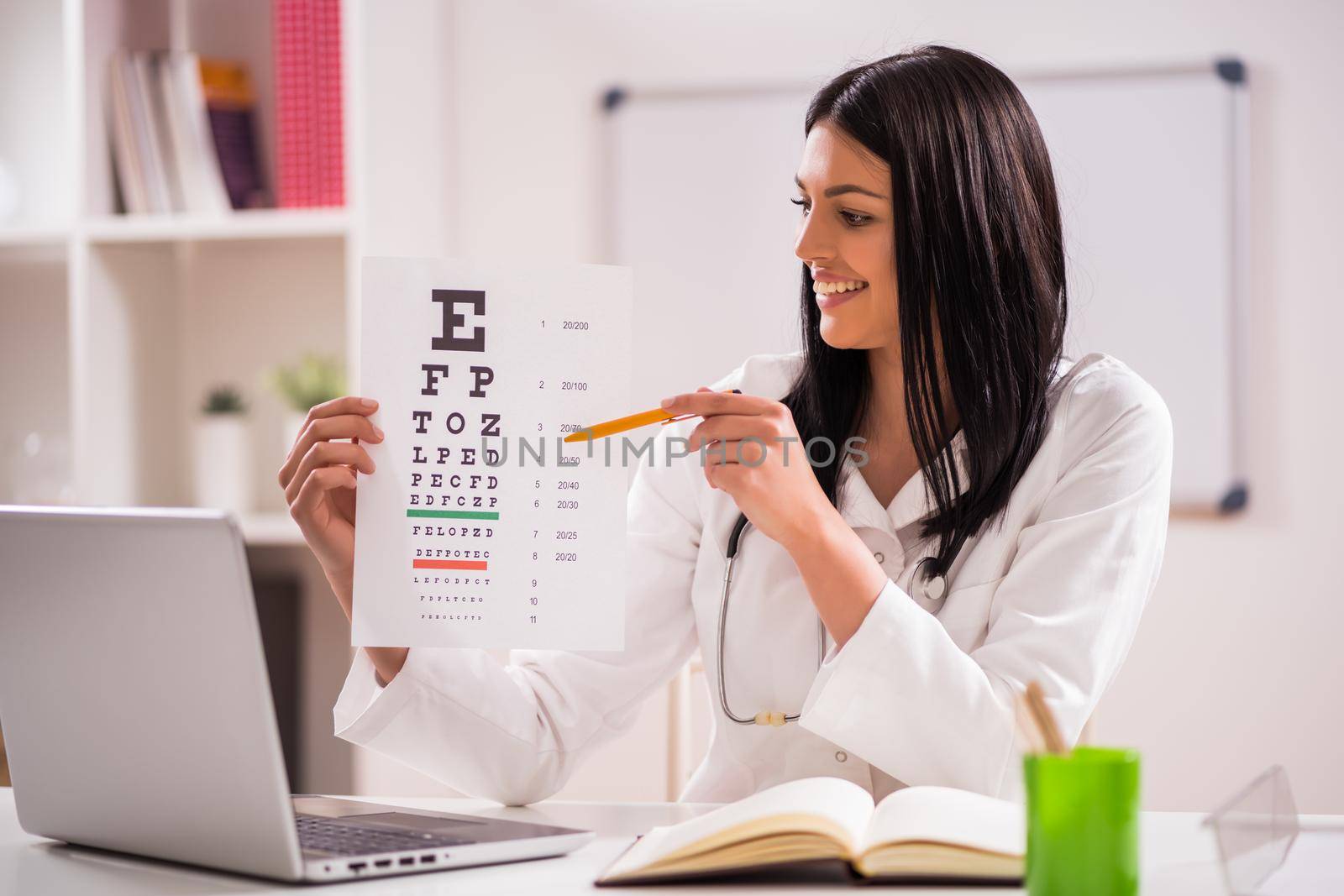 Young doctor is holding eye examination test in her office.