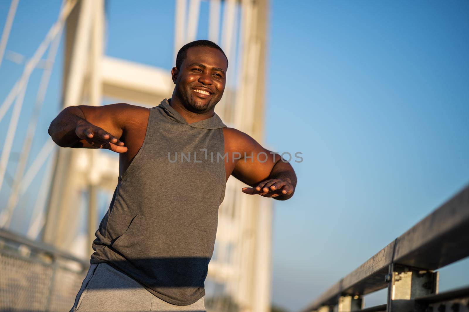 Young african-american man is exercising on the bridge in the city.