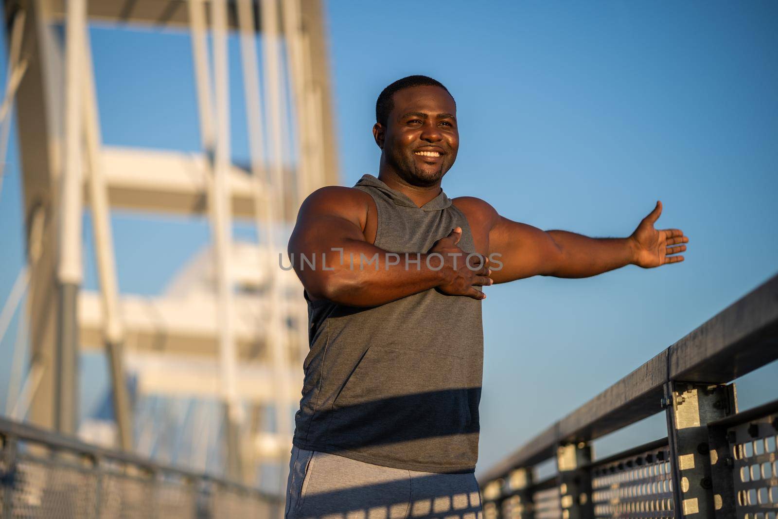 Young african-american man is exercising on the bridge in the city.