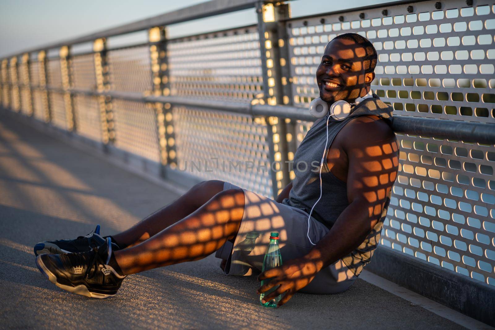 Portrait of young african-american man in sports clothing who is drinking water after jogging.