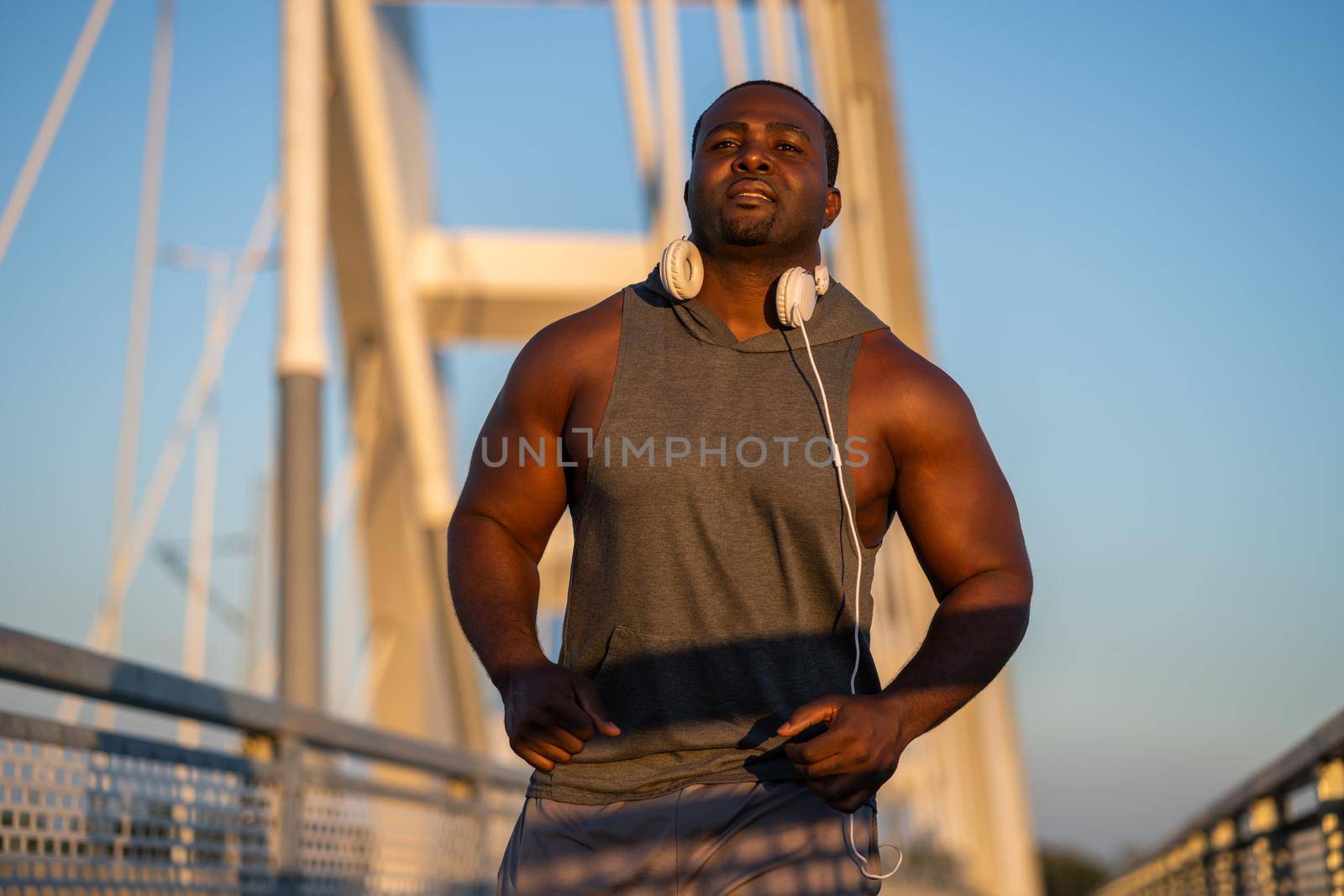 Young african-american man is jogging on the bridge in the city.