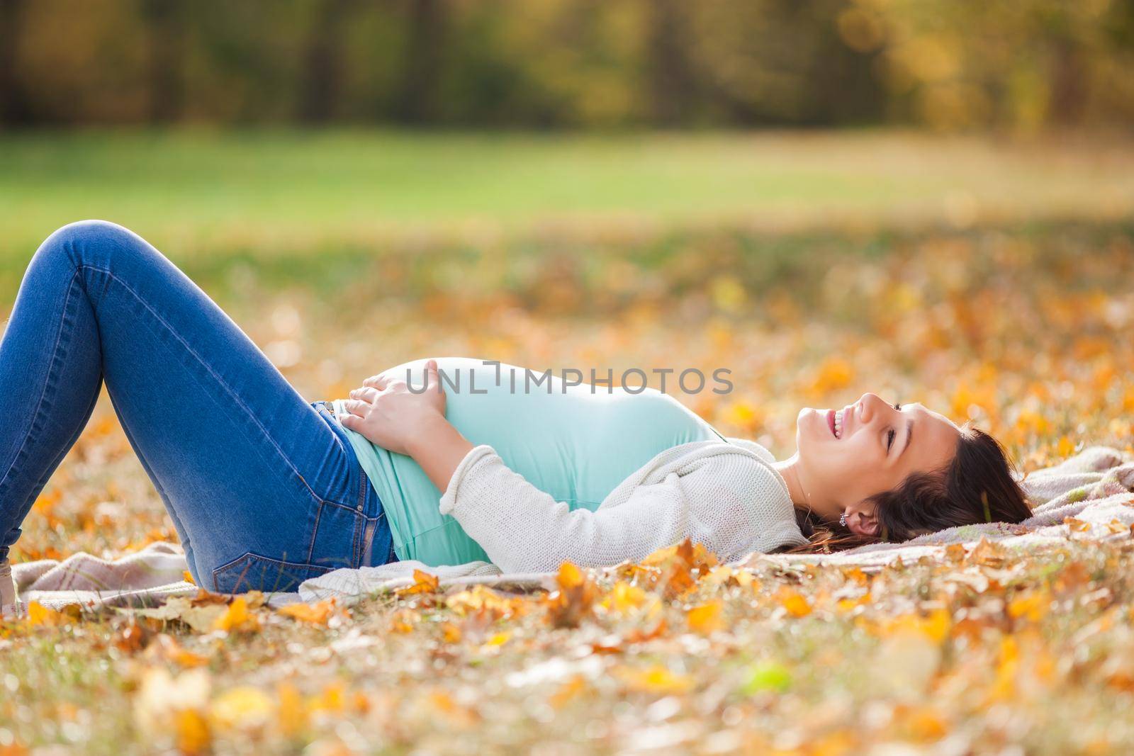 Happy pregnant woman relaxing in park.