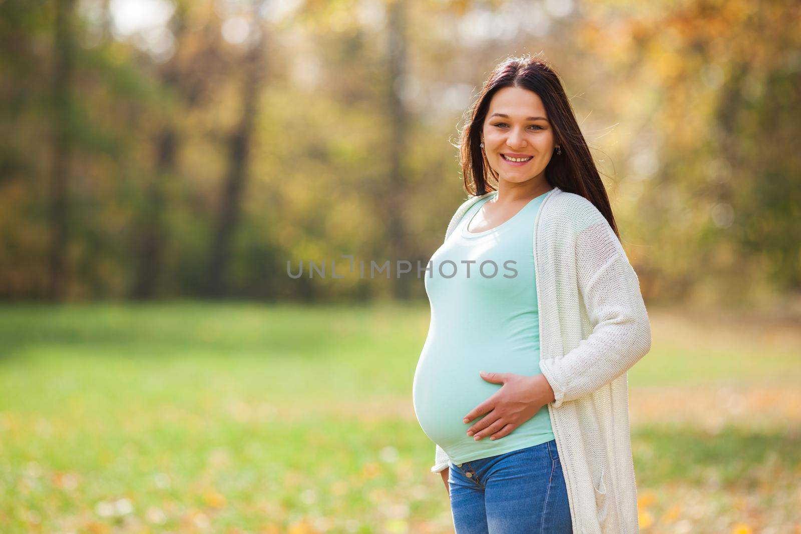 Happy pregnant woman relaxing in park.