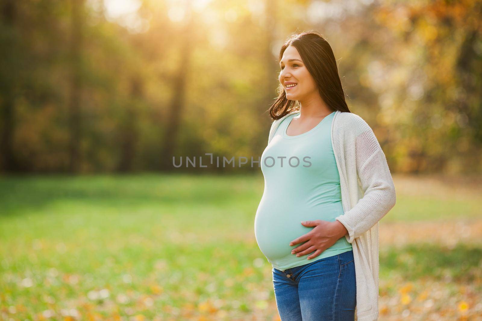 Happy pregnant woman relaxing in park.