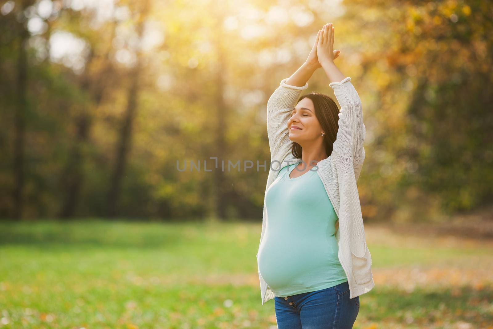 Pregnant woman relaxing in park. She is meditating.