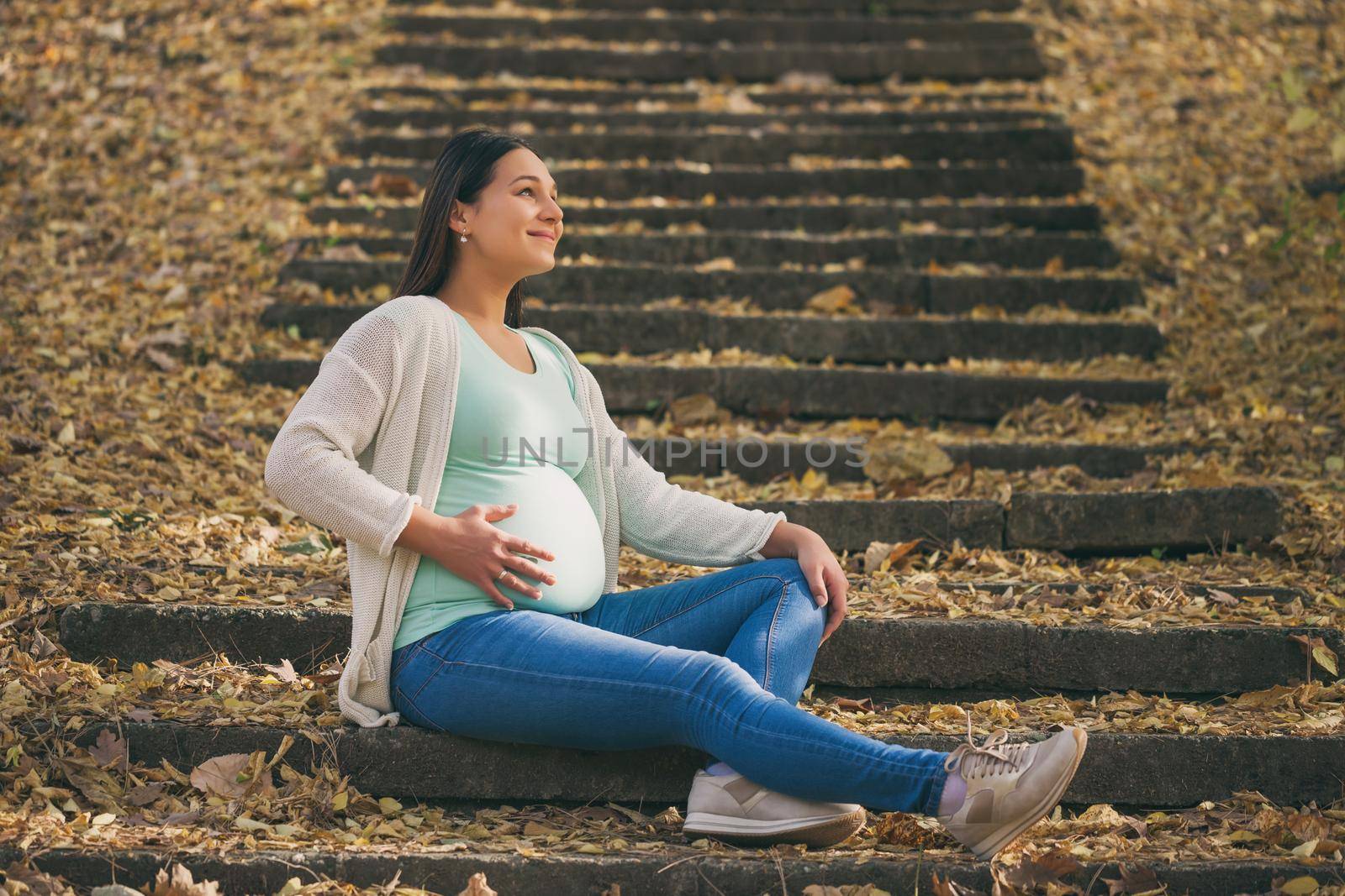 Happy pregnant woman relaxing in park.