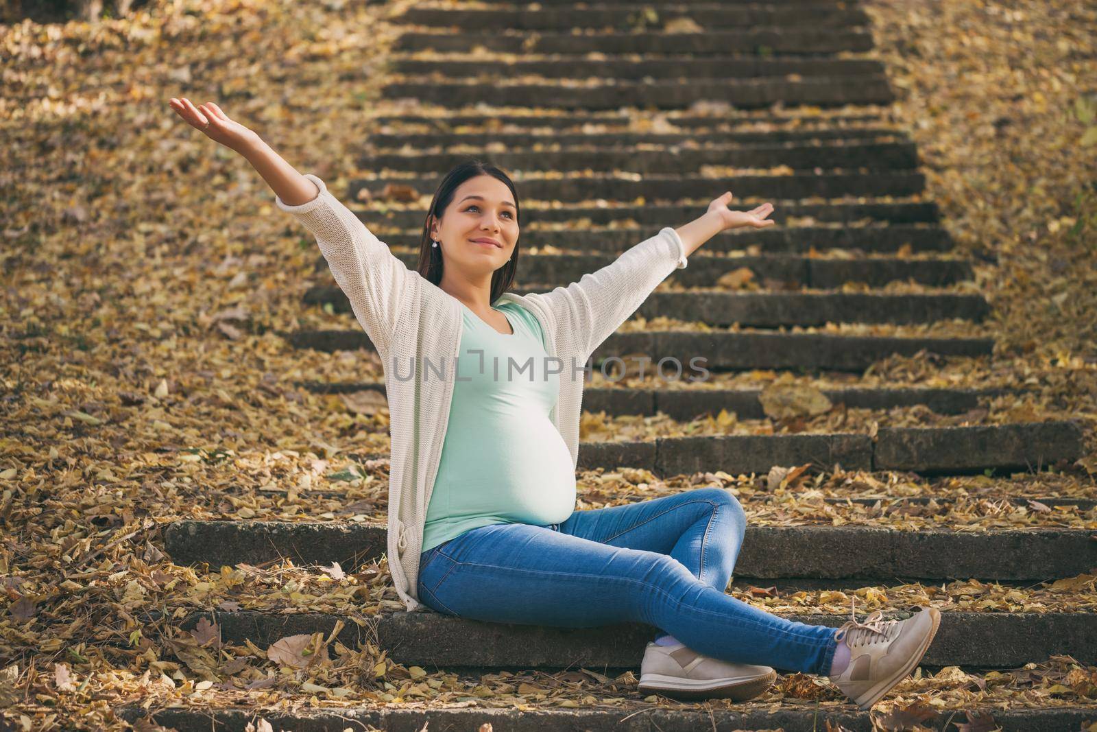 Happy pregnant woman relaxing in park.