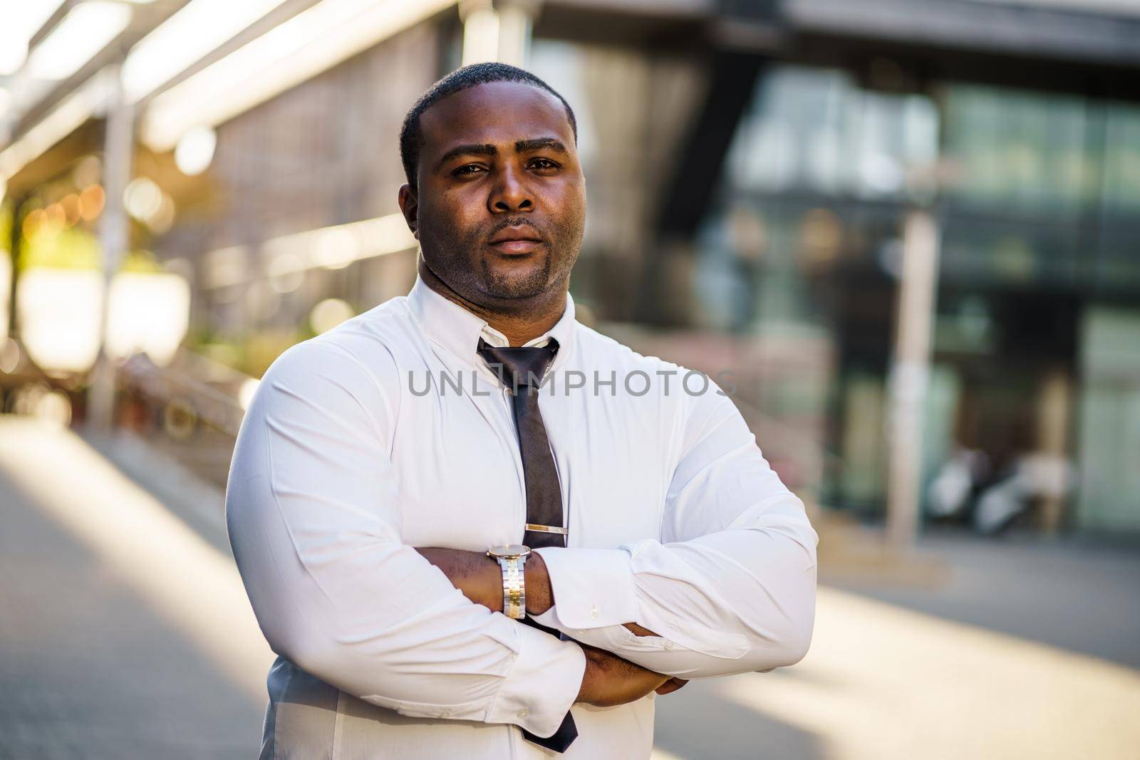 Portrait of serious african-american businessman in front of company building.