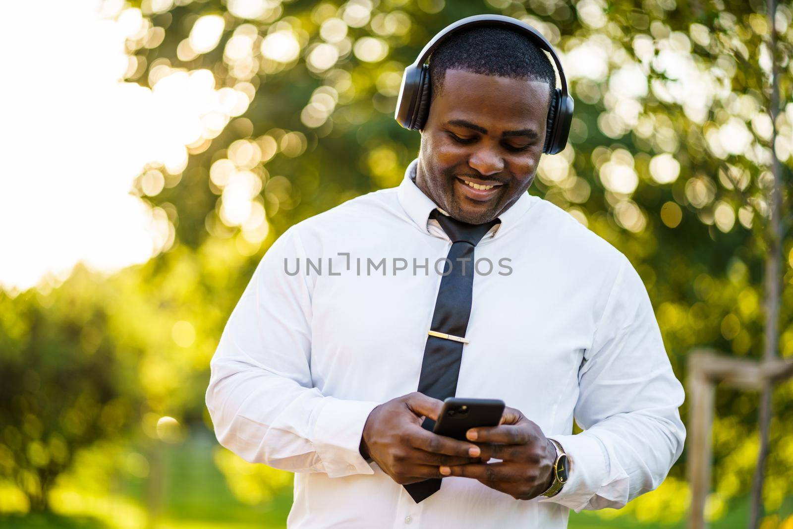 Portrait of happy african-american businessman who is using smartphone.