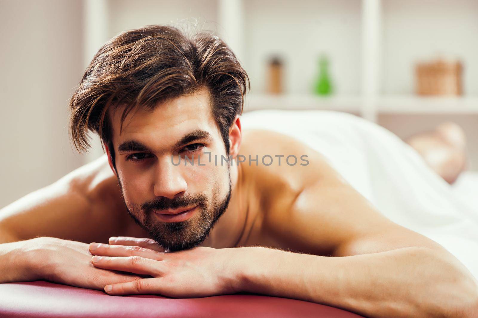 Young man is relaxing after massage on spa treatment.