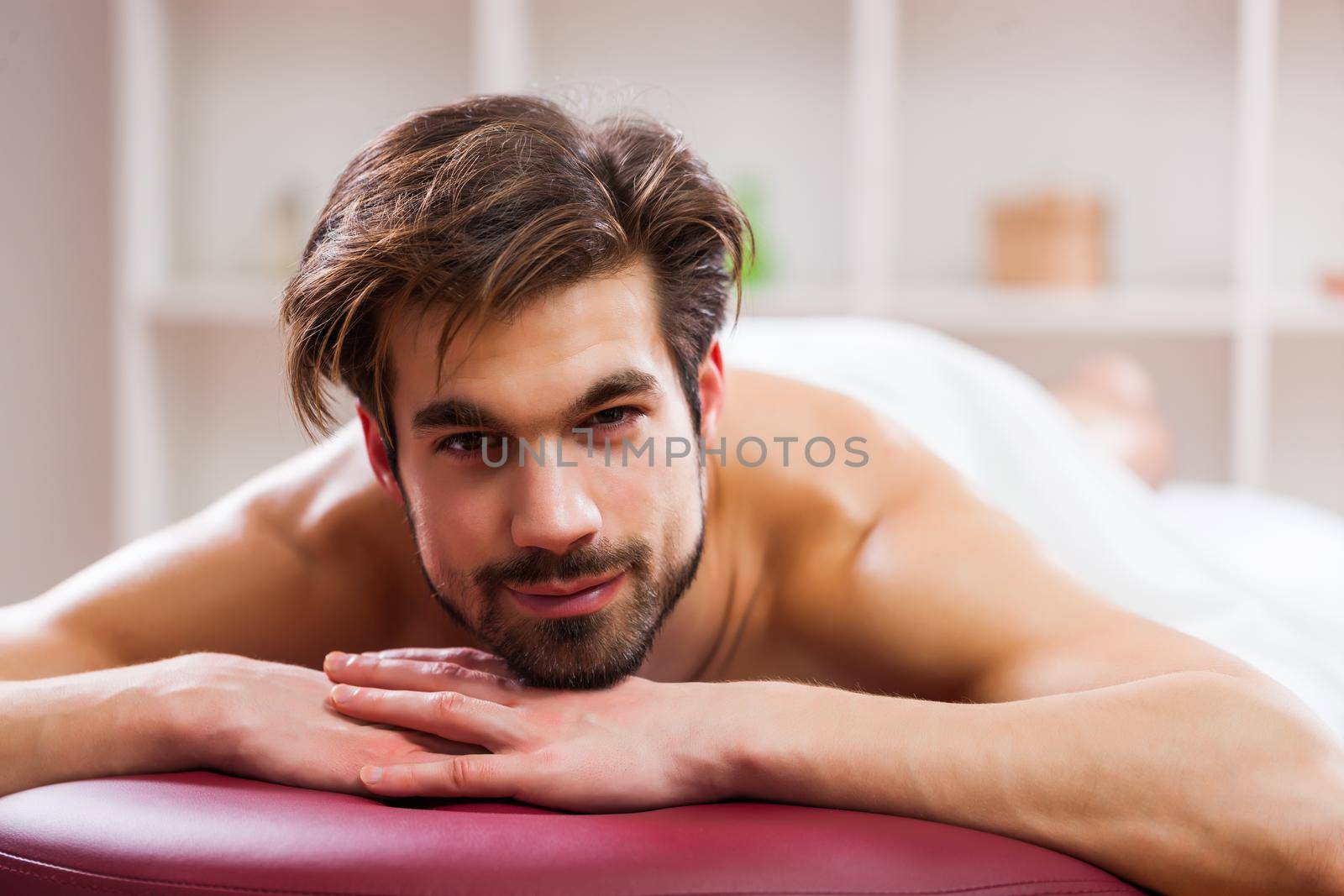 Young man is relaxing after massage on spa treatment.