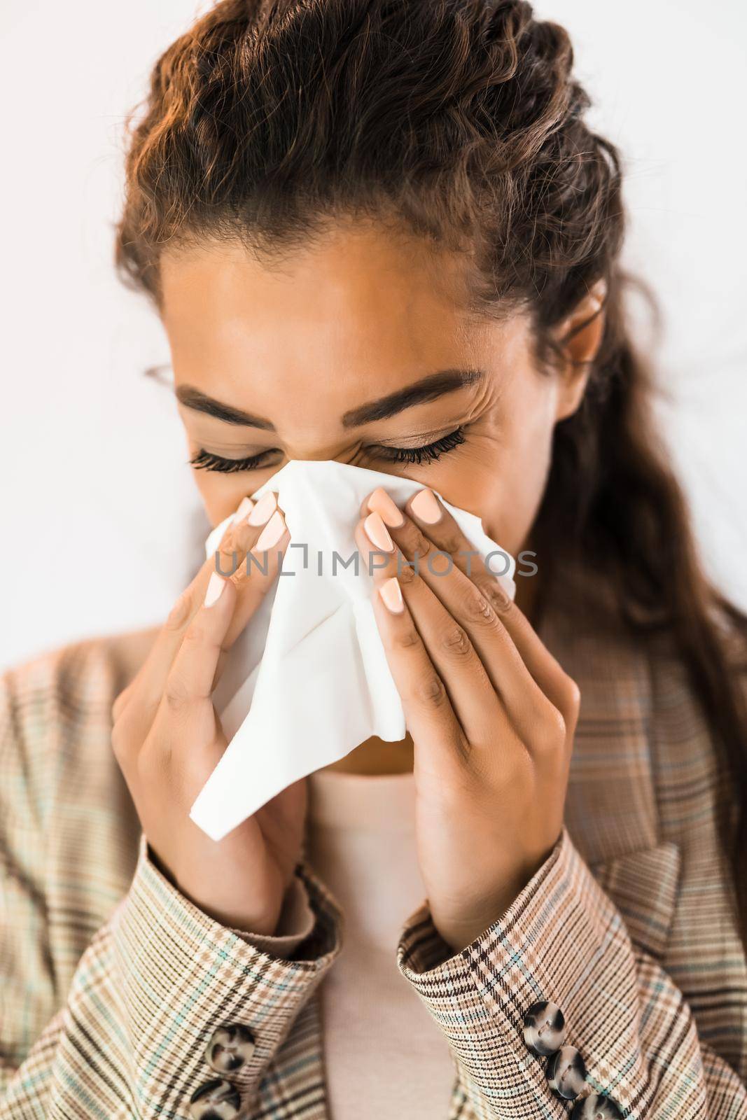 Portrait of beautiful african american woman who has allergy problem. She is blowing nose.