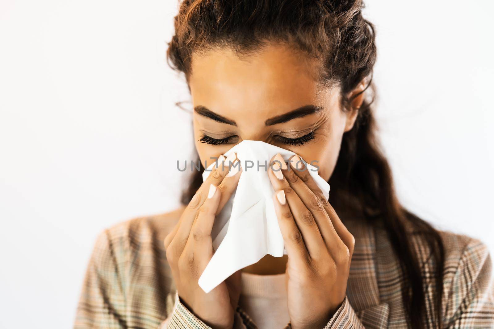 Portrait of beautiful african american woman who has allergy problem. She is blowing nose.