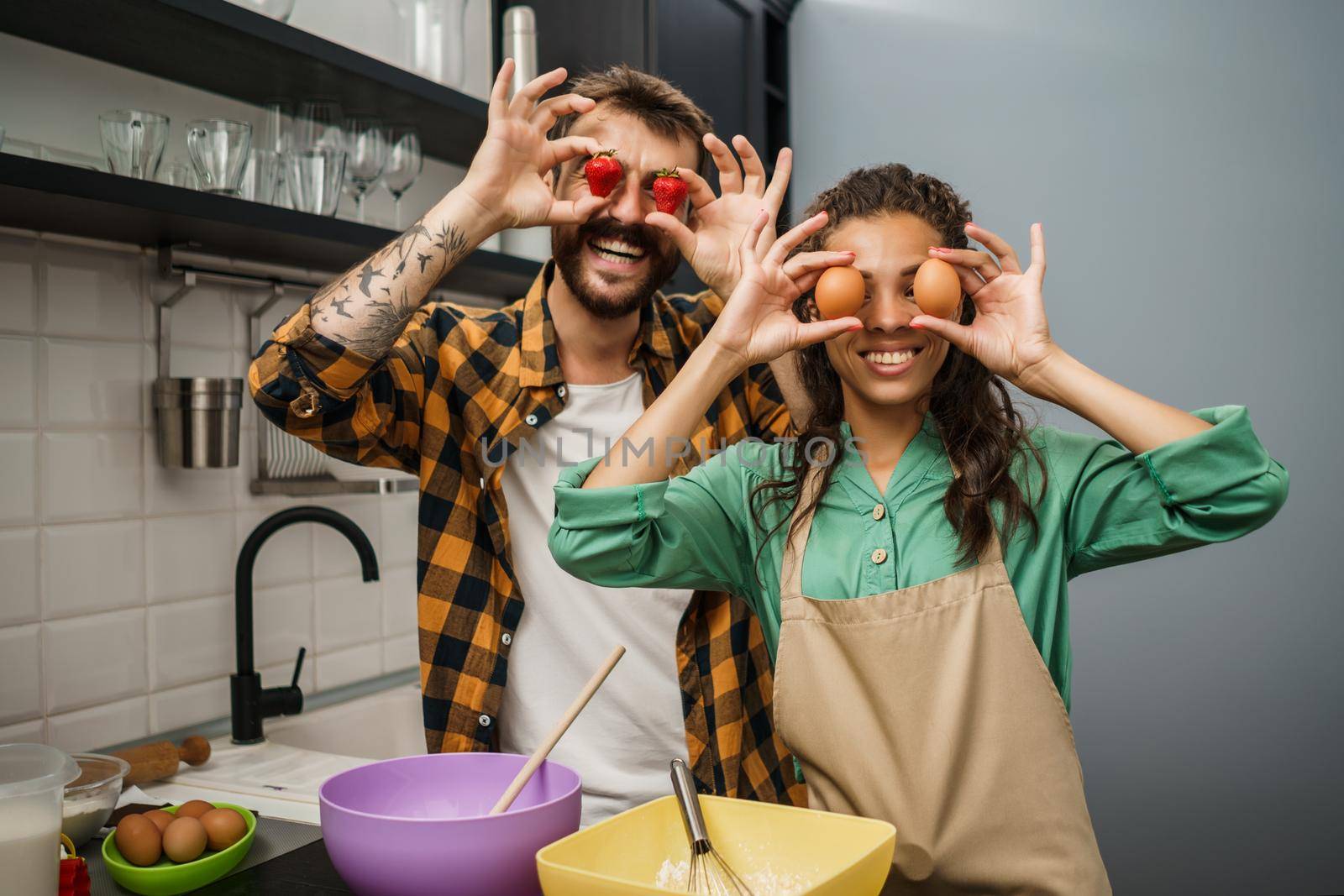 Happy multiracial couple cooking in their kitchen. They are making cookies and having fun.