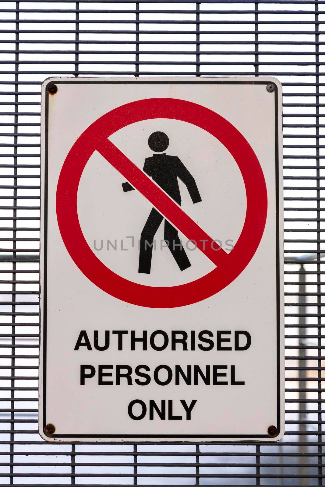 An authorised personnel only safety sign on a mesh metal gate on a stairwell