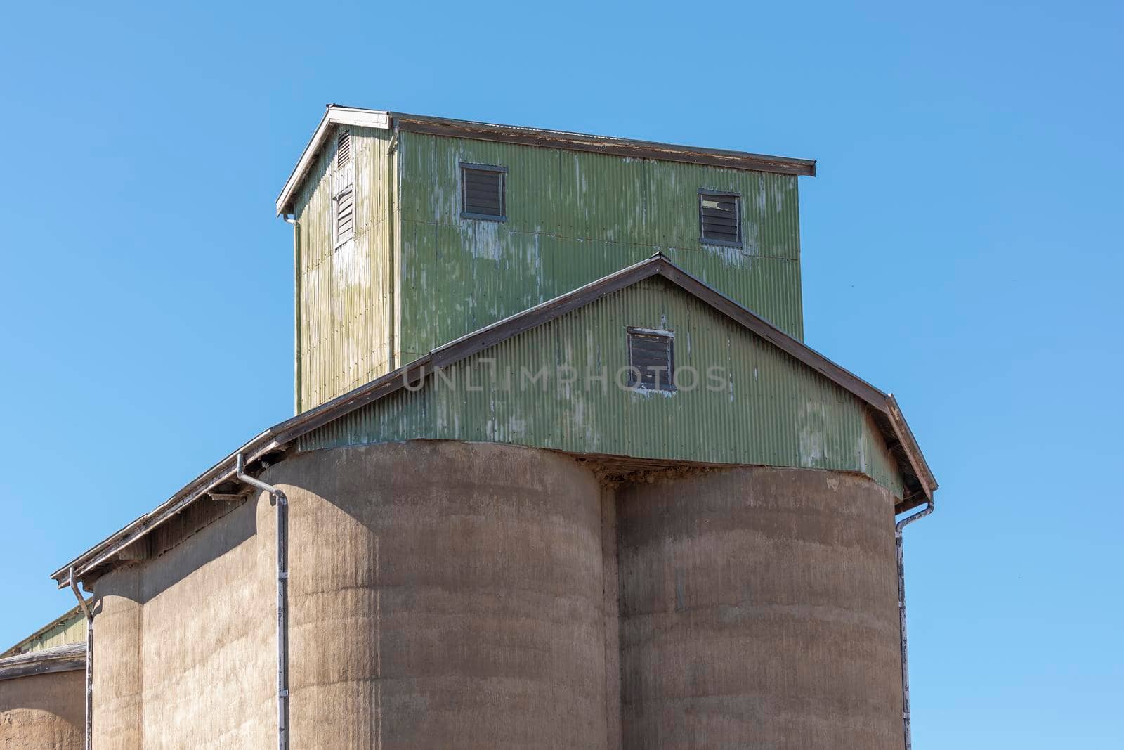 An old green corrugated iron building on the top of a concrete storage silo at a flour mill