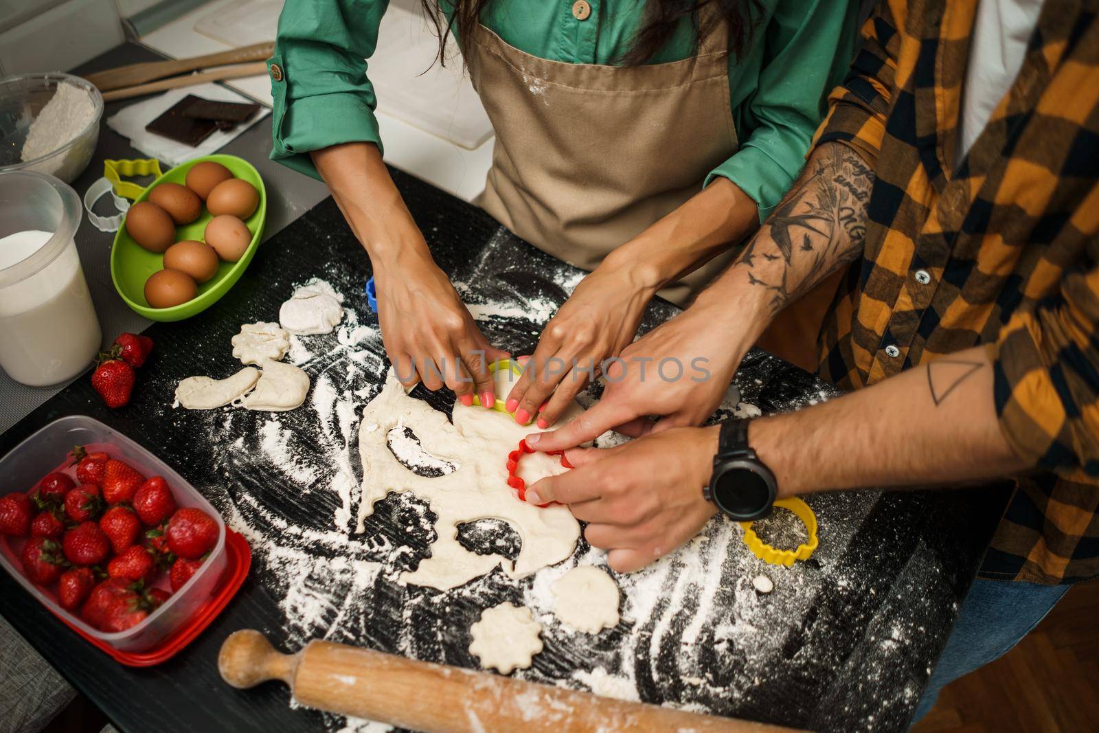 Close-up of multiracial couple making cookies in their kitchen.