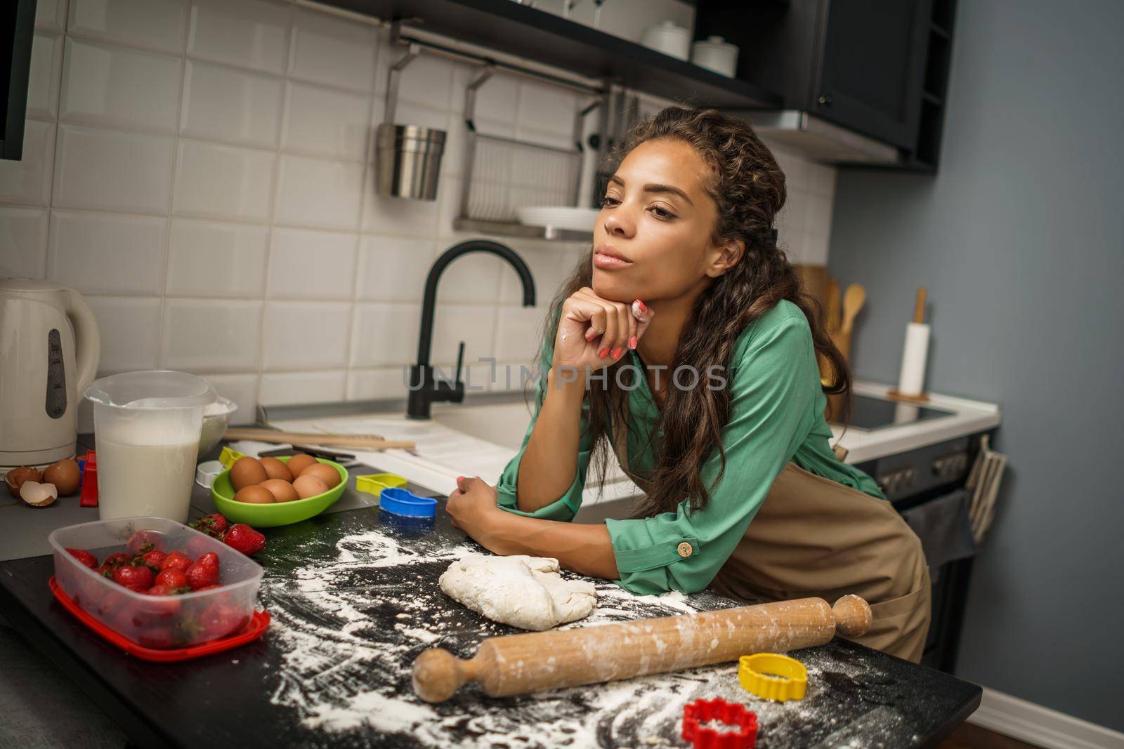 Young african-american woman is making cookies in her kitchen. She is tired of cooking.