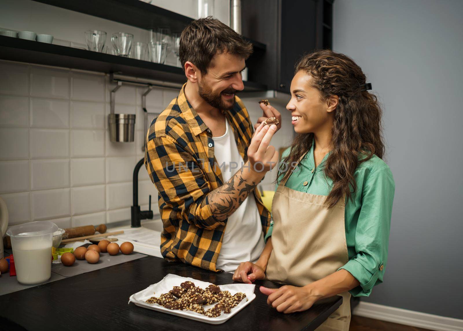 Happy multiracial couple have made cookies in their kitchen.