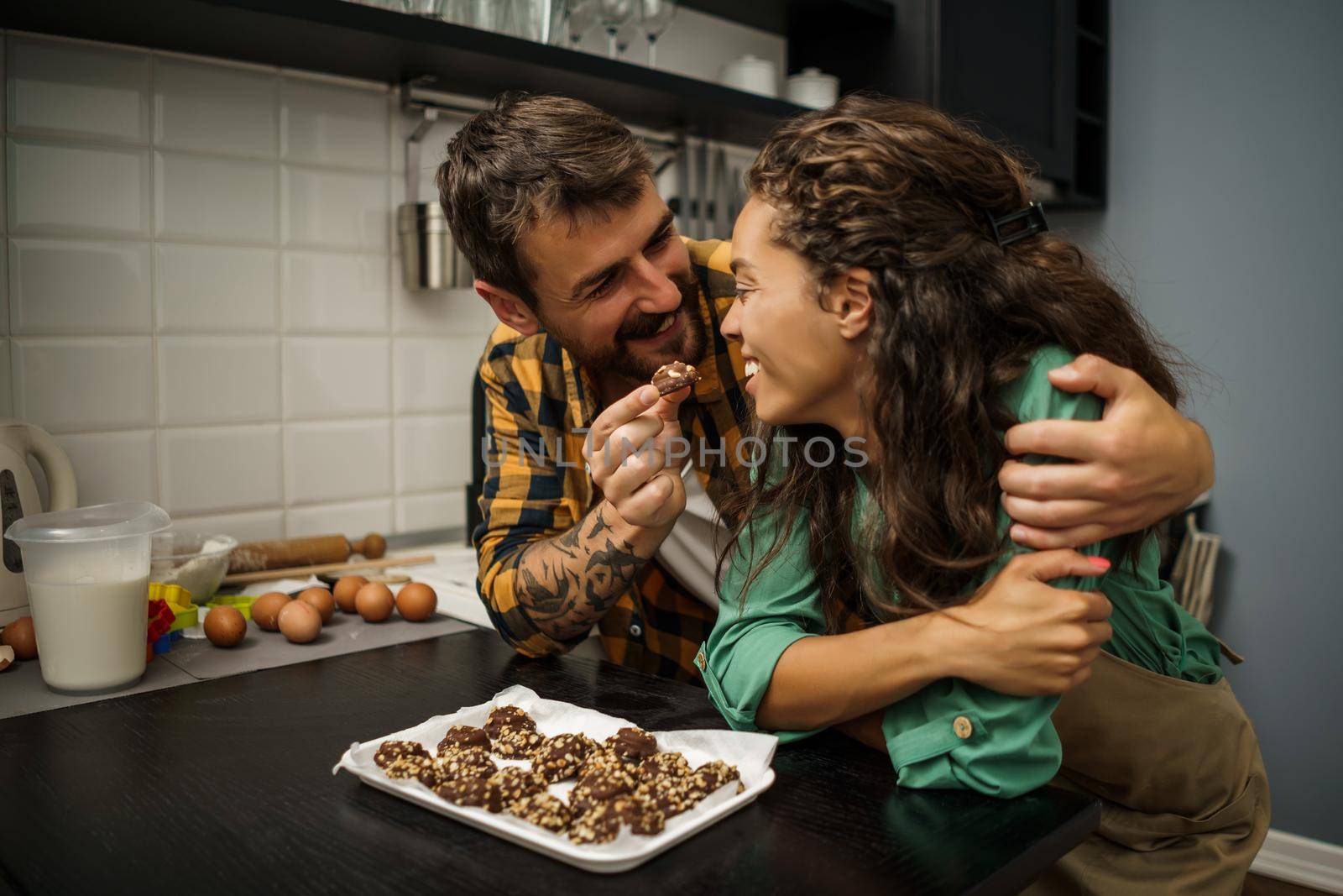Happy multiracial couple have made cookies in their kitchen.
