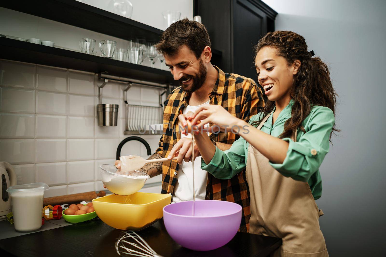 Happy multiethnic couple cooking in their kitchen. They are making cookies.