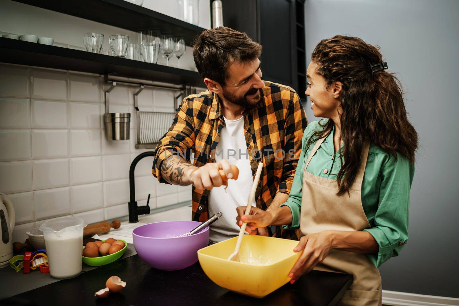 Happy multiethnic couple cooking in their kitchen. They are making cookies.