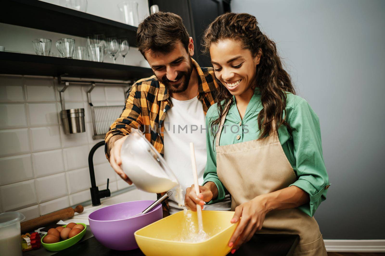 Happy multiethnic couple cooking in their kitchen. They are making cookies.