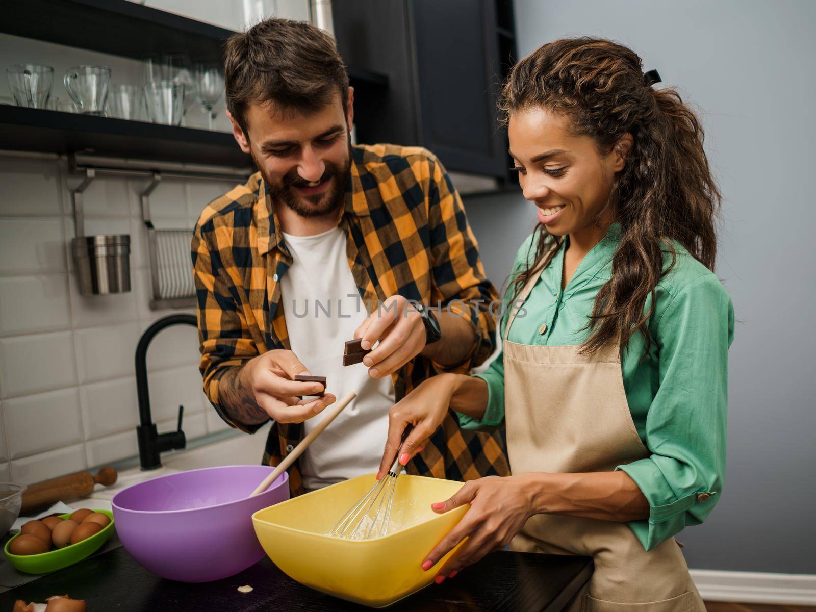 Happy multiethnic couple cooking in their kitchen. They are making cookies.
