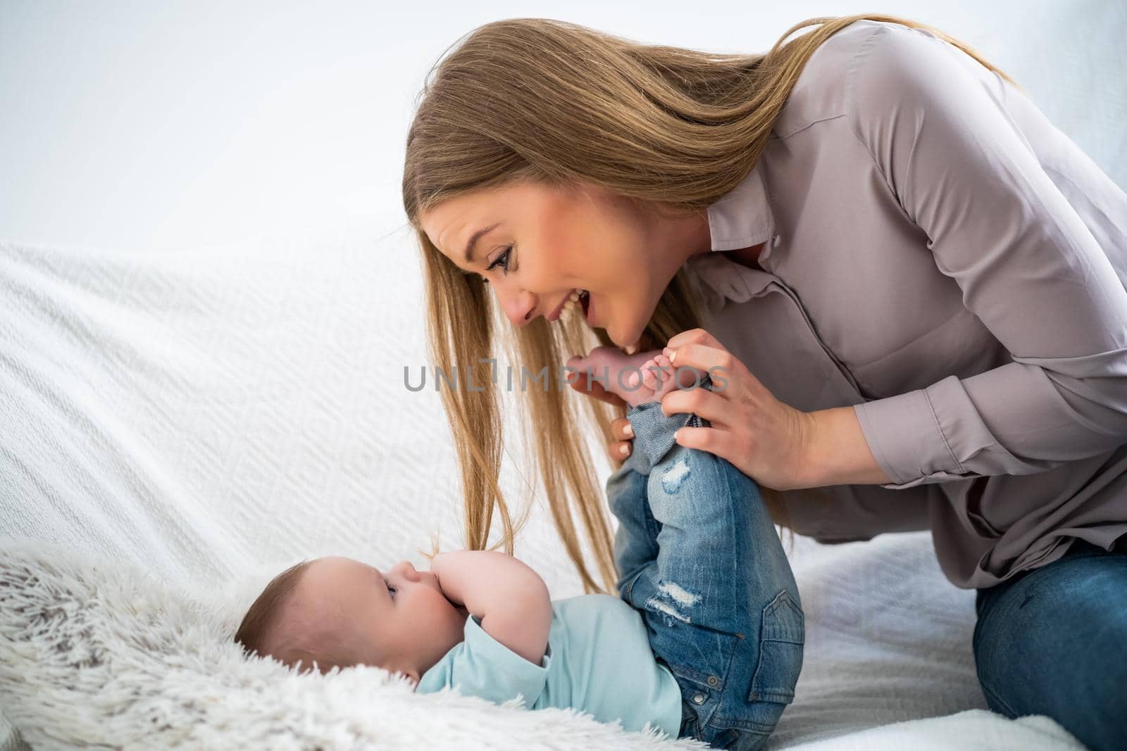 Happy mother and her baby boy playing at home.