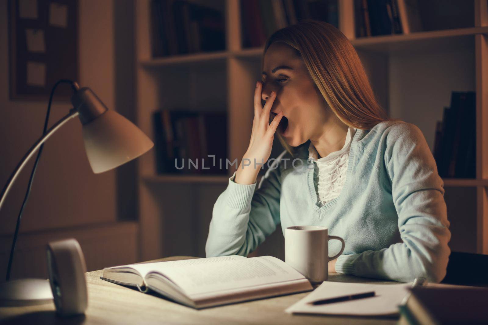 Tired student is learning at home. She is sleepy.