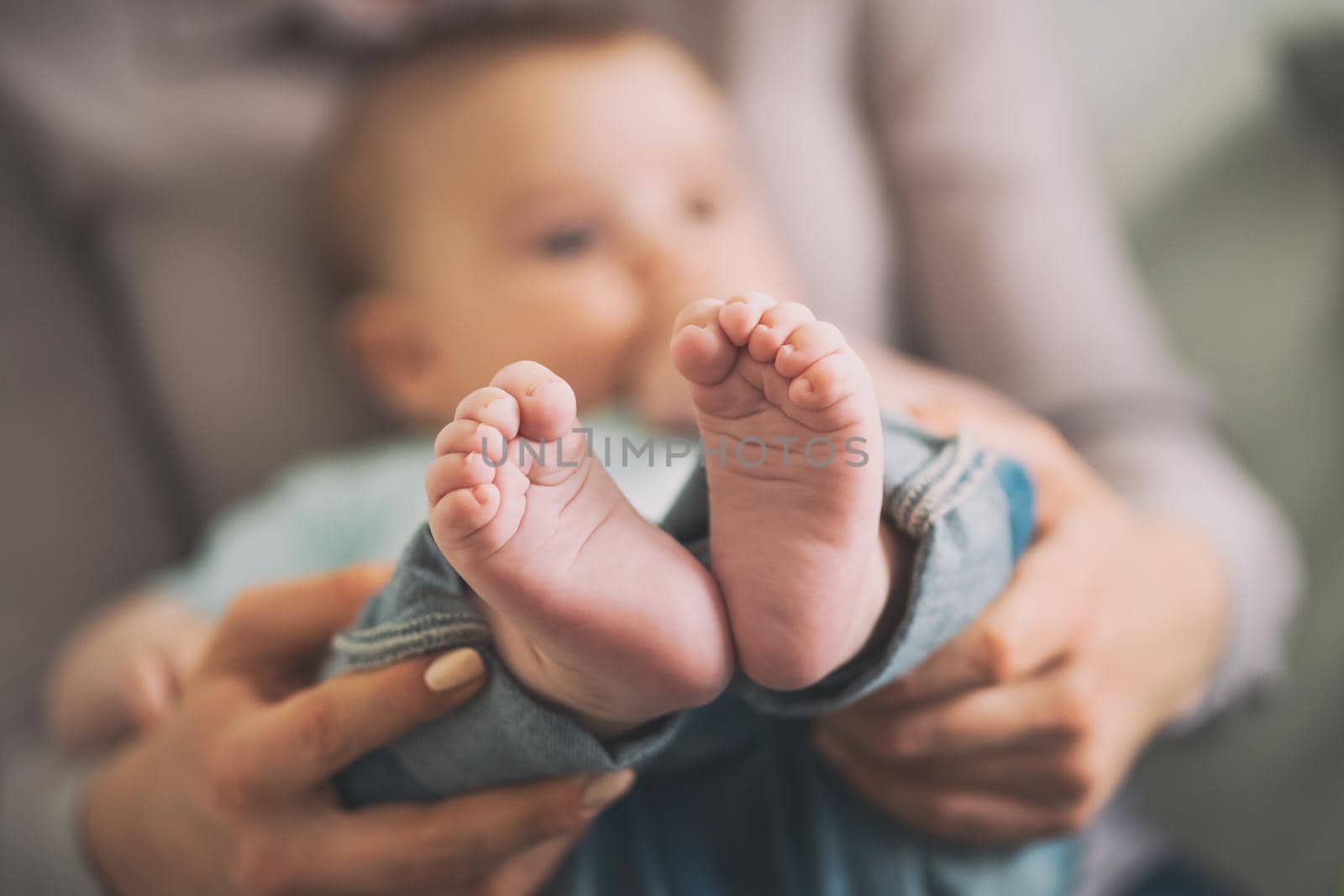 Close up image of baby feet. Mother is holding feet of her baby boy.