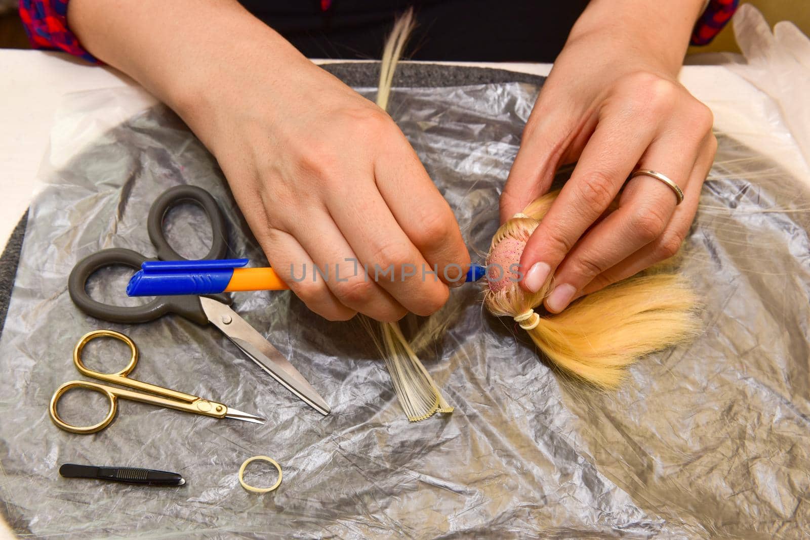female hands and homemade tool on the table, how to make a hairstyle for a doll, hobby concept by karpovkottt