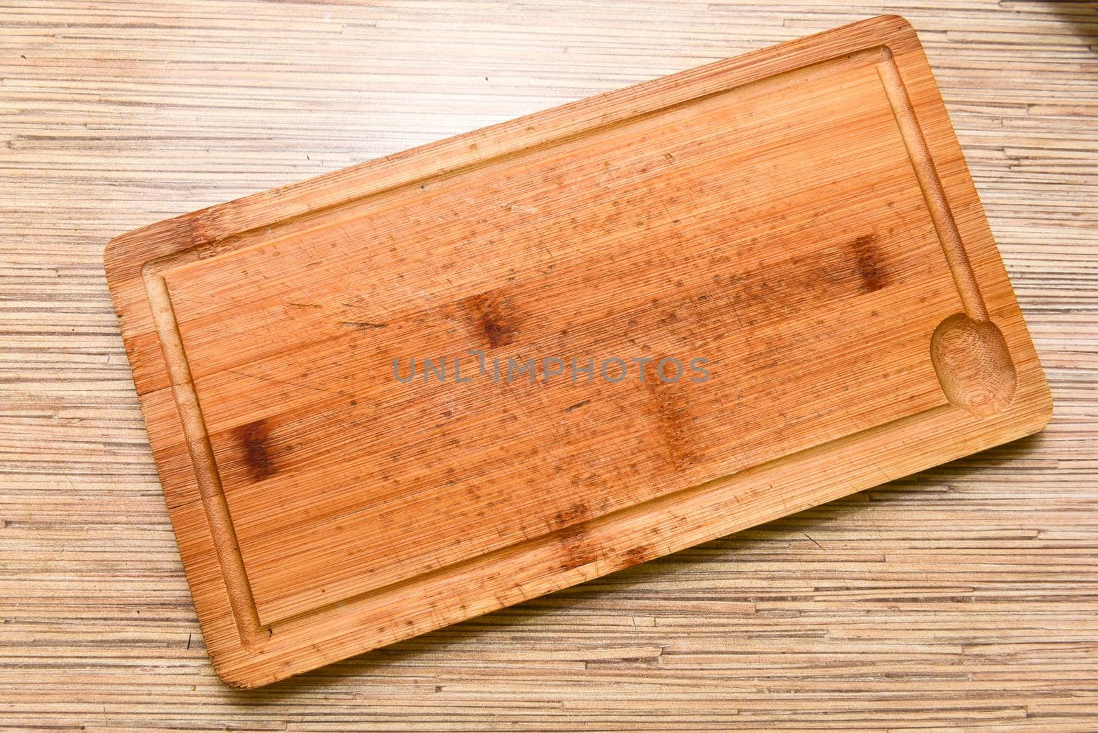 Old chopping board on wooden background top view.