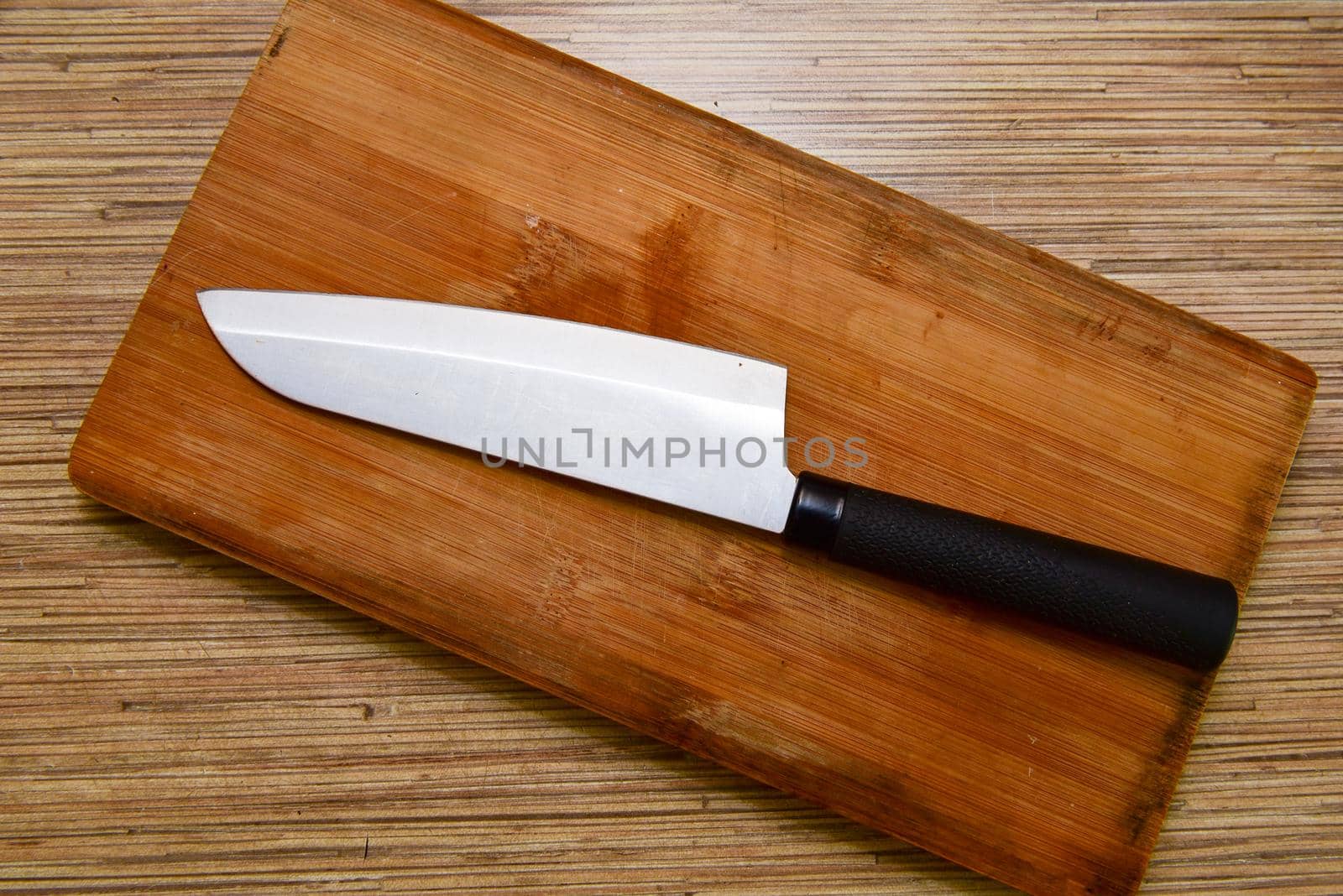 Cutting board and a kitchen knife on wooden background. Top view.