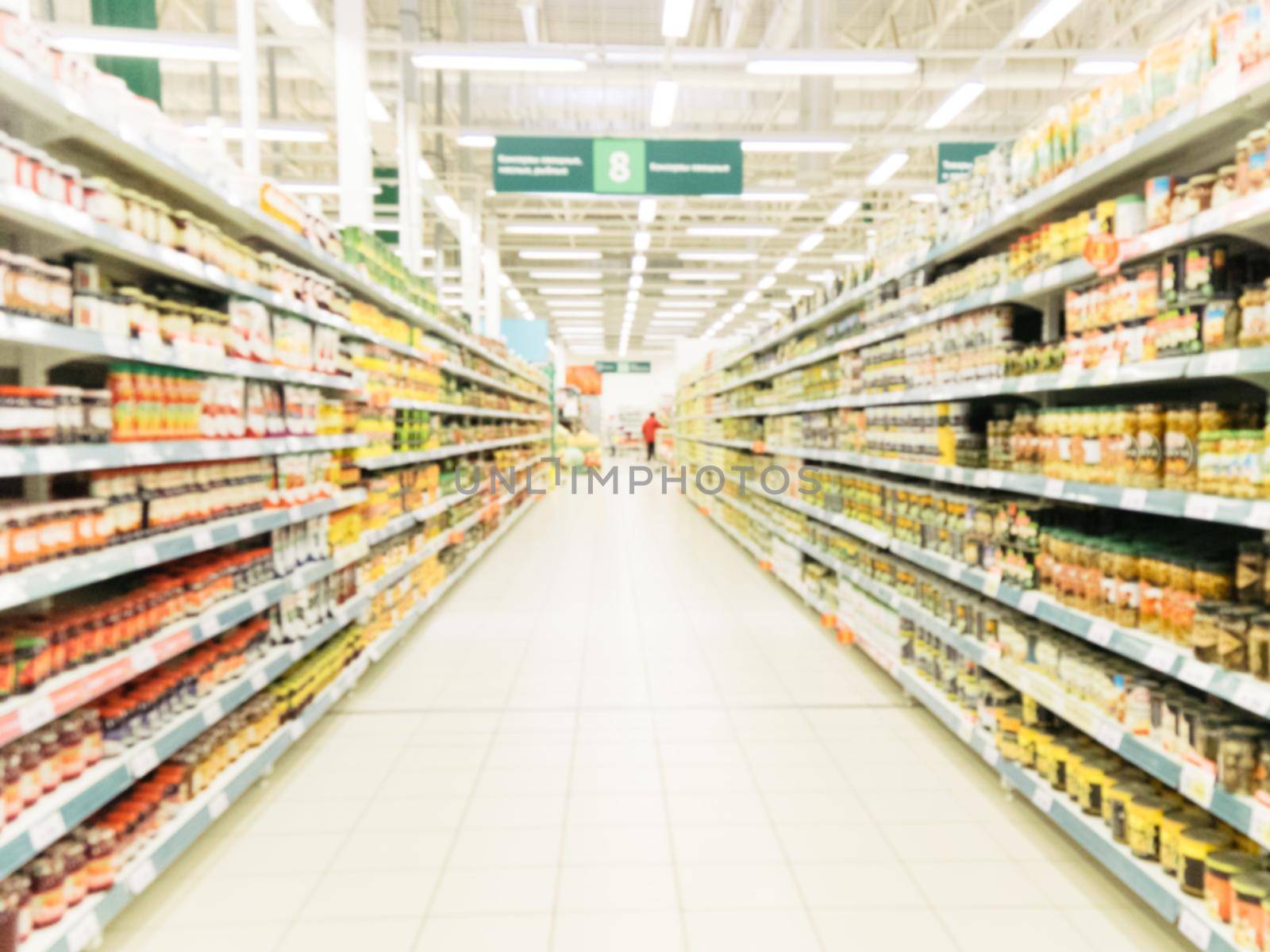 Abstract blurred supermarket aisle with colorful shelves and unrecognizable customers as background