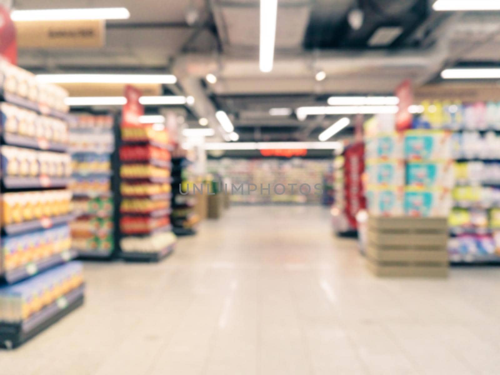 Abstract blurred supermarket aisle with colorful shelves and unrecognizable customers as background