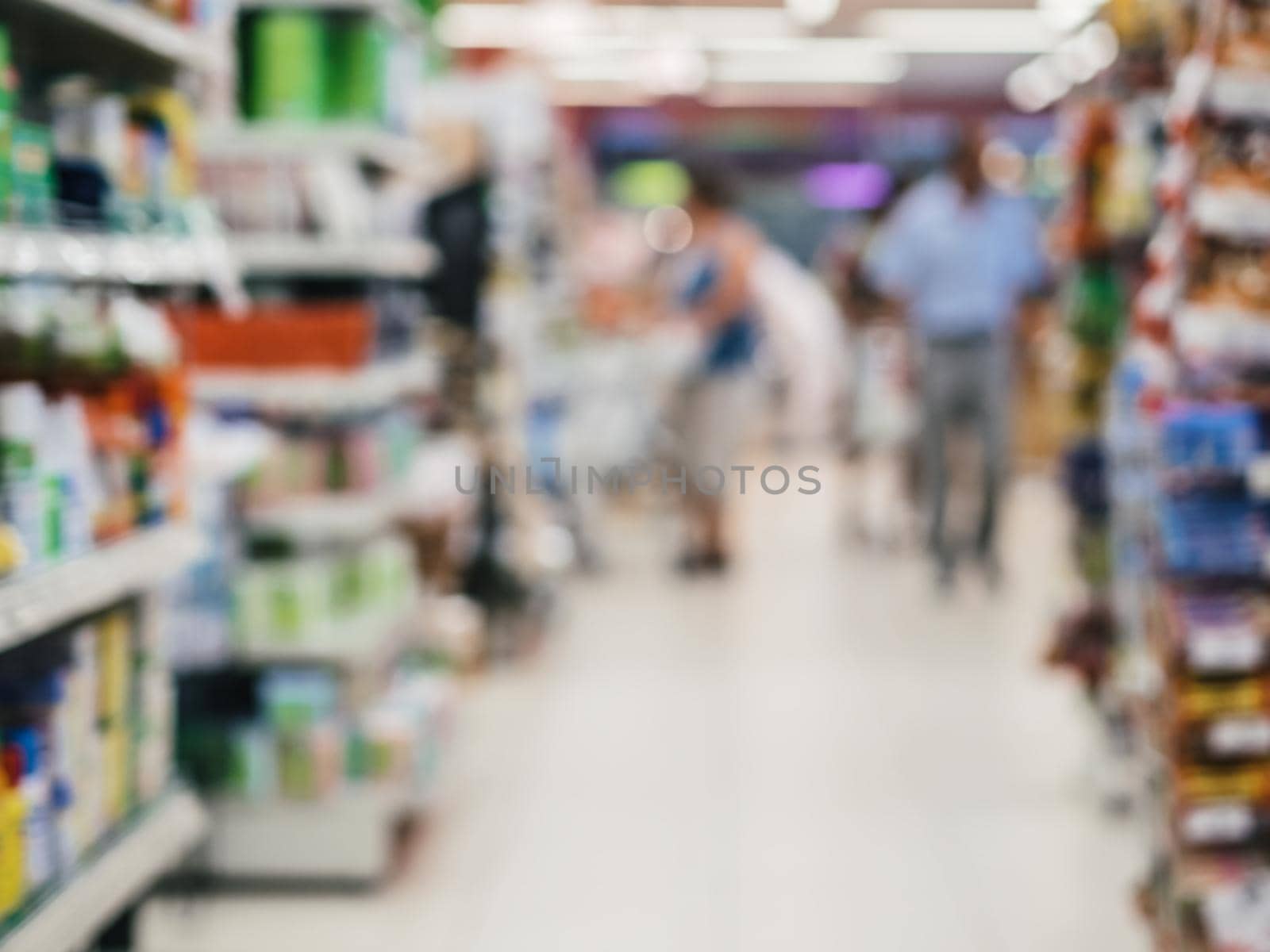 Abstract blurred supermarket aisle with colorful shelves and unrecognizable customers as background